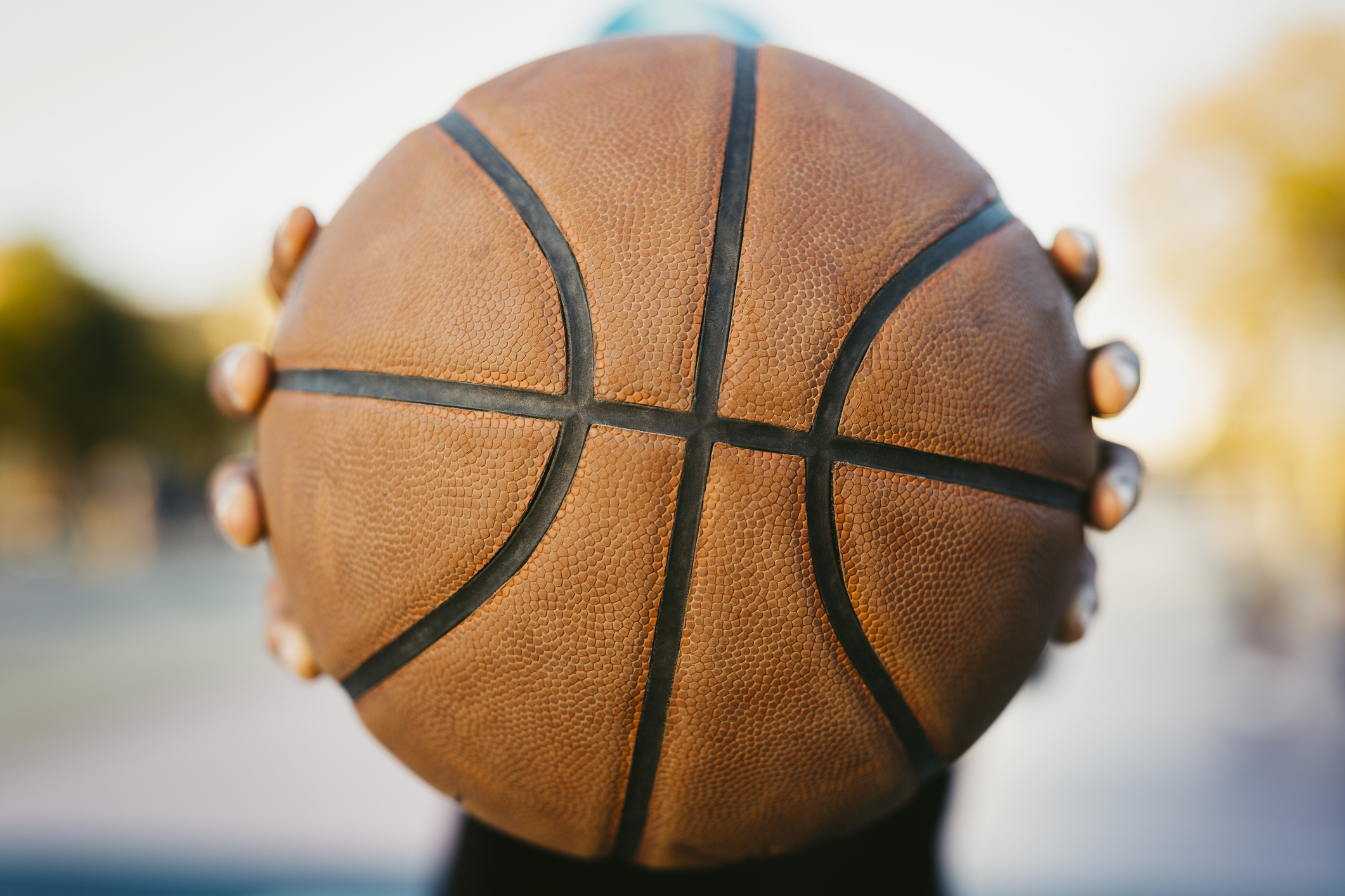 Close-up of a person holding a basketball blocking their face
