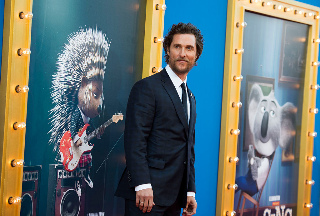 Matthew McConaughey in a suit at the &#x27;Sing 2&#x27; premiere with character posters in the background