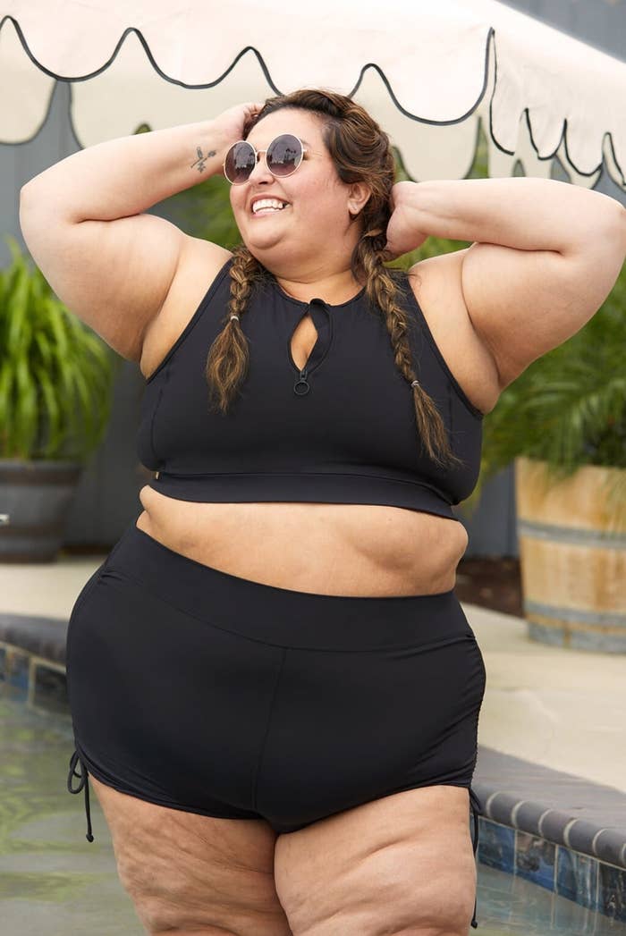 Woman in black keyhole swimsuit posing confidently by pool