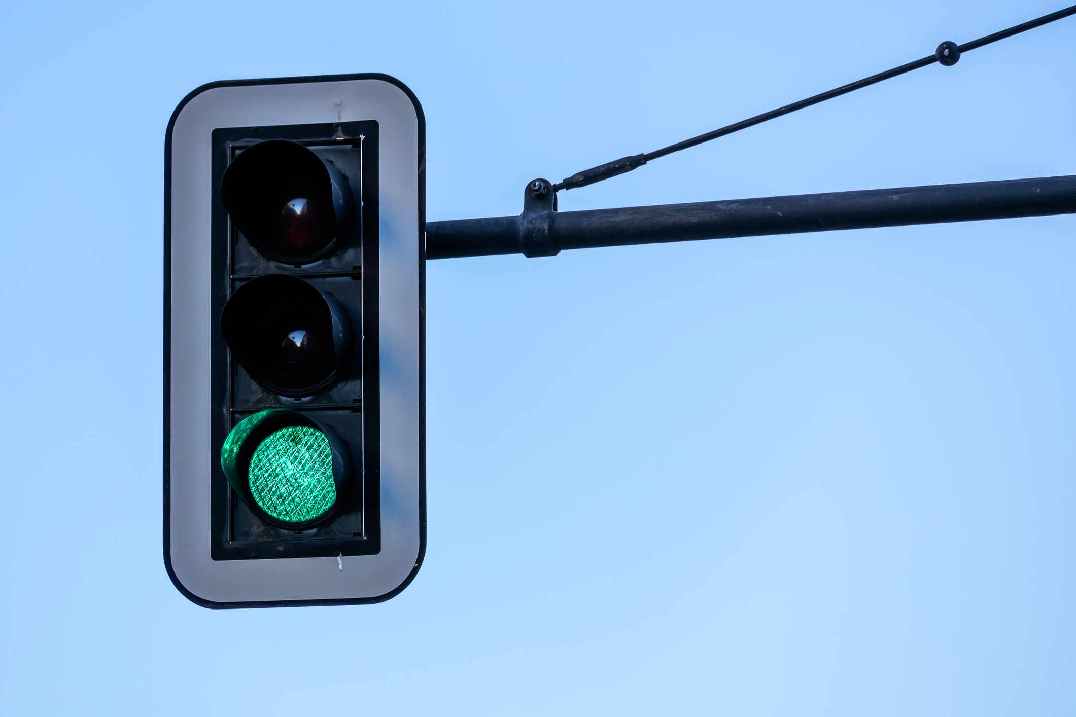 Traffic light against a clear sky with the green light illuminated