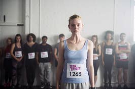 Woman in tank top with "Teen Spirit 1265" bib, standing confidently with group of people in background
