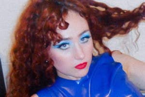 Chappell Roan posing with dramatic makeup and a shiny blue top, twisting her curly hair around her finger.