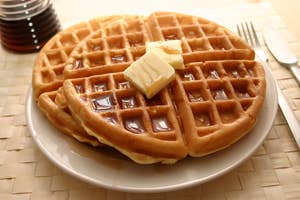 a plate of waffles topped with syrup and two pats of butter