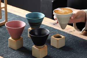 four cone-shaped cups in a square base with a model grabbing one of them