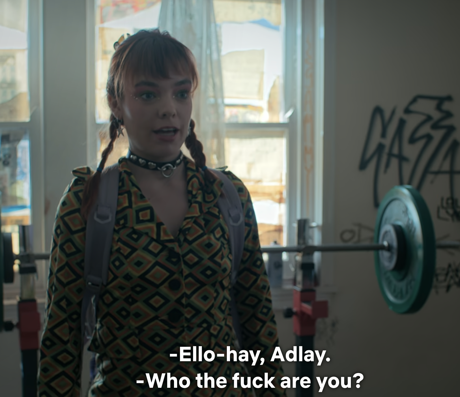 Eddie from Stranger Things is surprised in a cluttered room, with graffiti and exercise equipment