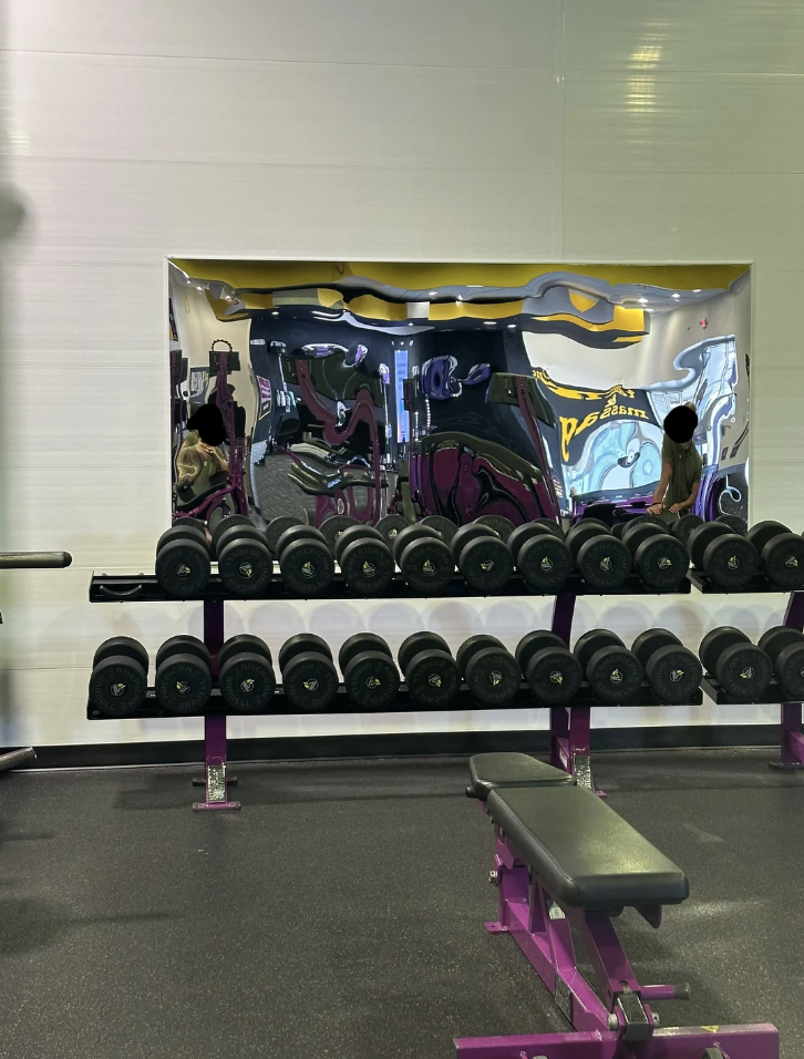 A distorted reflection of a gym with weights in a wavy mirror, creating a surreal effect