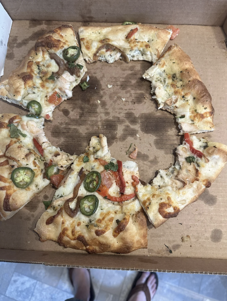 Partial pizza with toppings in a box, viewed from above