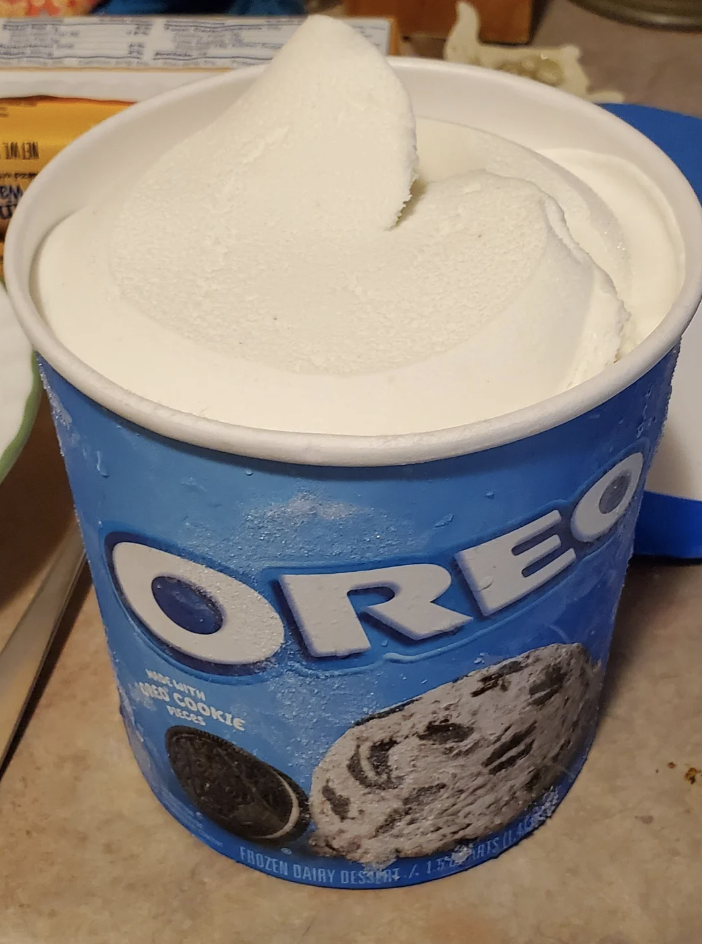 A carton of Oreo ice cream with a swirled top, opened and ready to be served