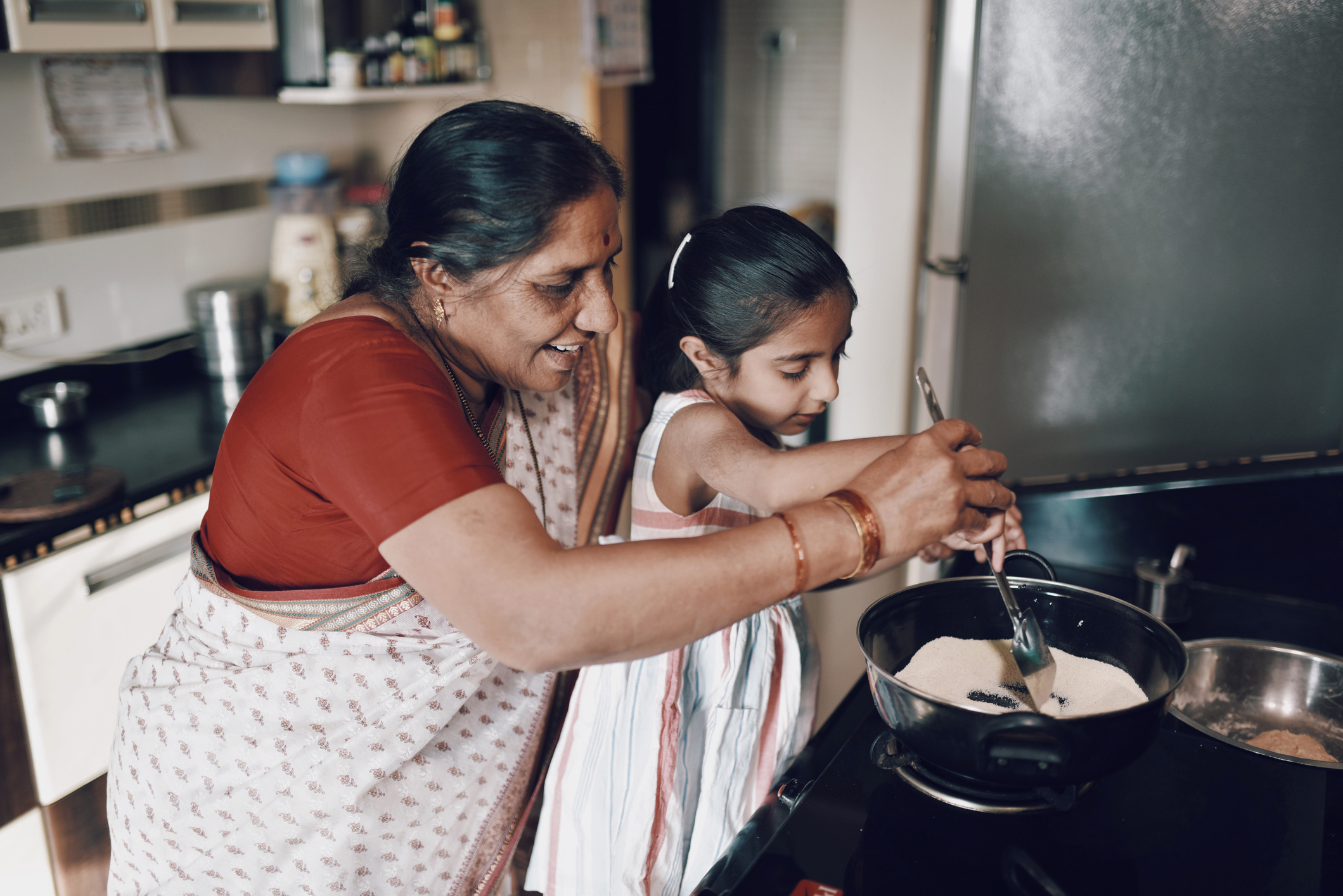 A grandmother and granddaughter cooking together in a kitchen