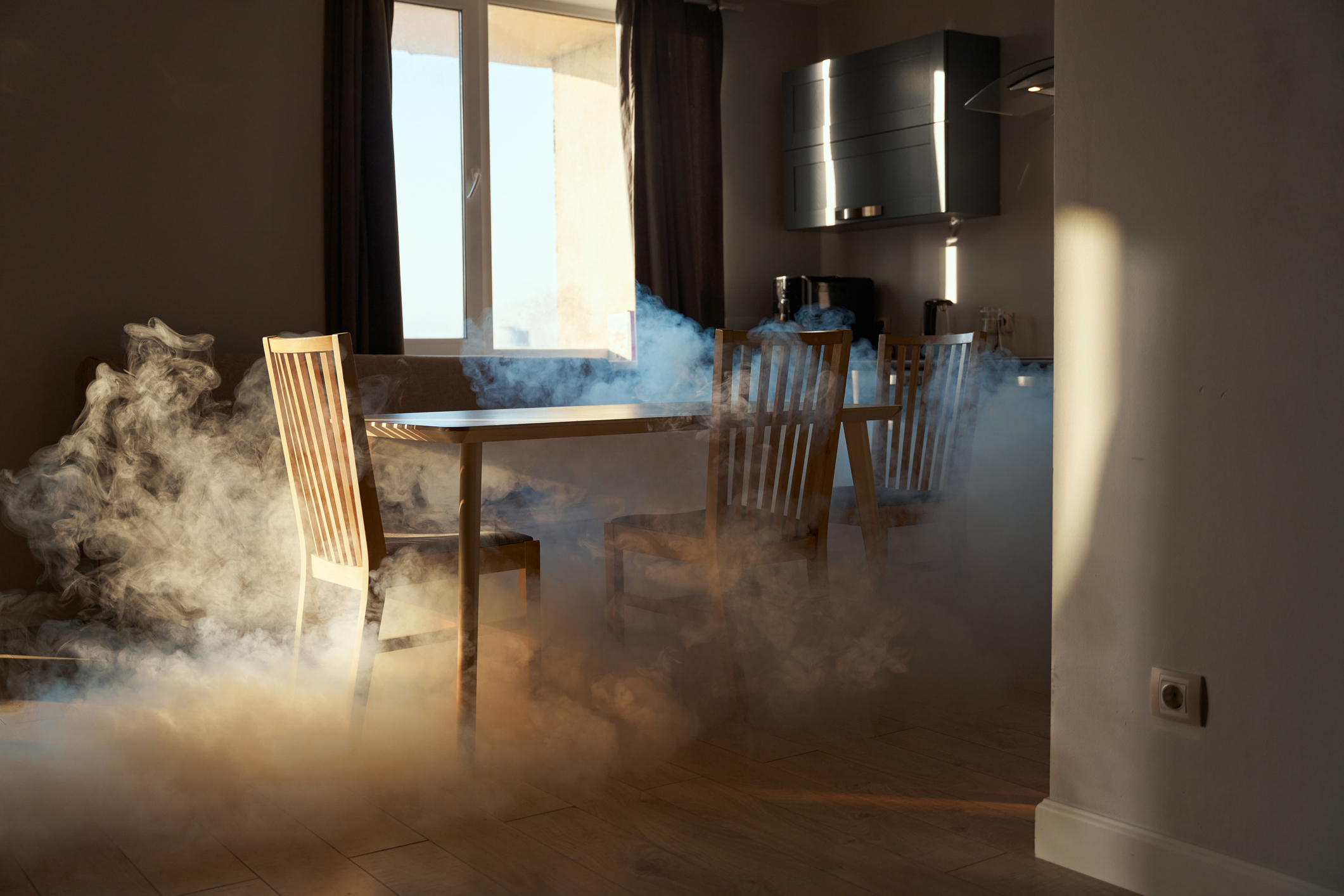 Kitchen with smoke near a dining table and chairs