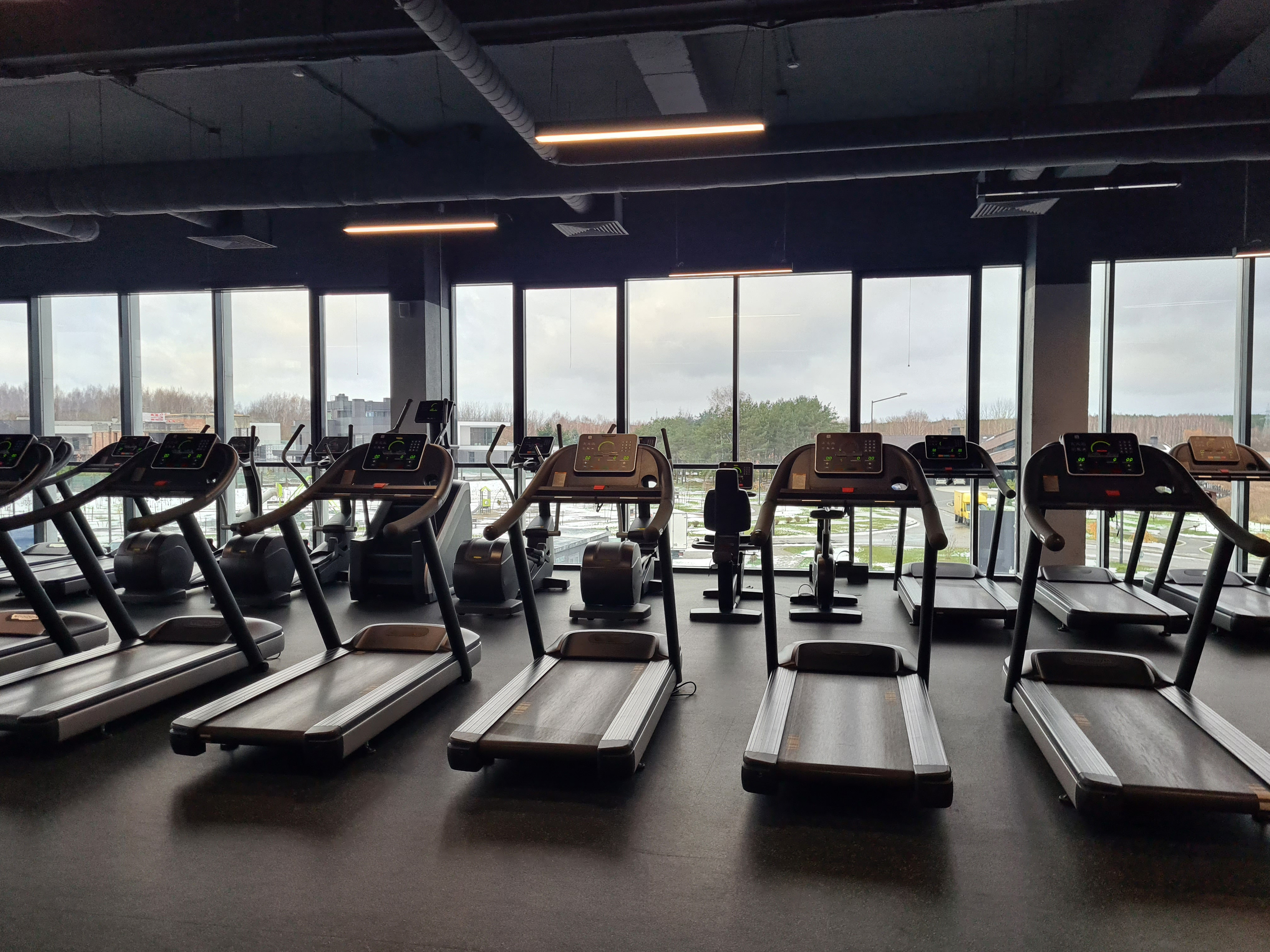 A modern gym with various treadmills and exercise machines but nobody&#x27;s there working out