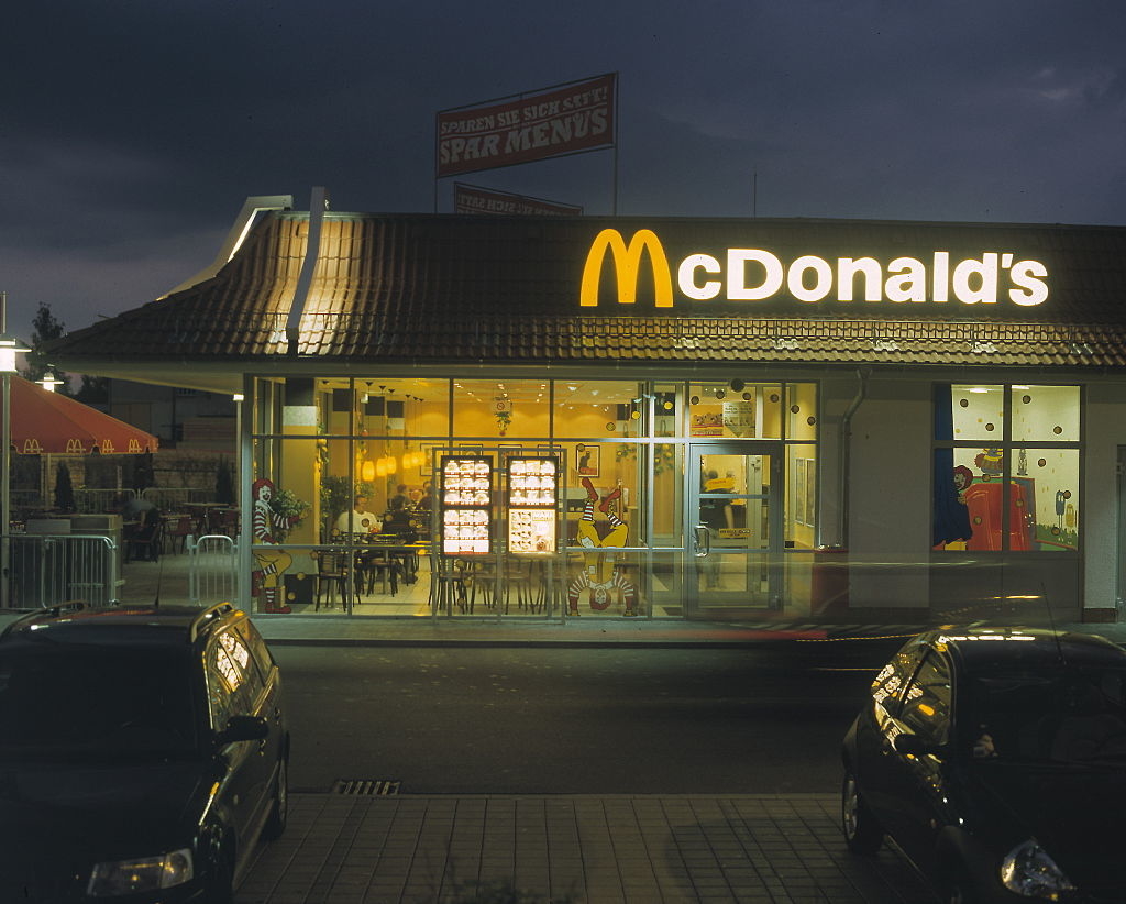 Exterior of a McDonald&#x27;s restaurant at twilight with illuminated signage and interior lights