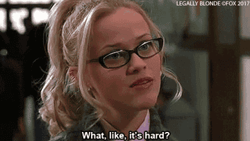 Elle Woods from Legally Blonde, portrayed by Reese Witherspoon, is sceptically smiling in a courtroom scene
