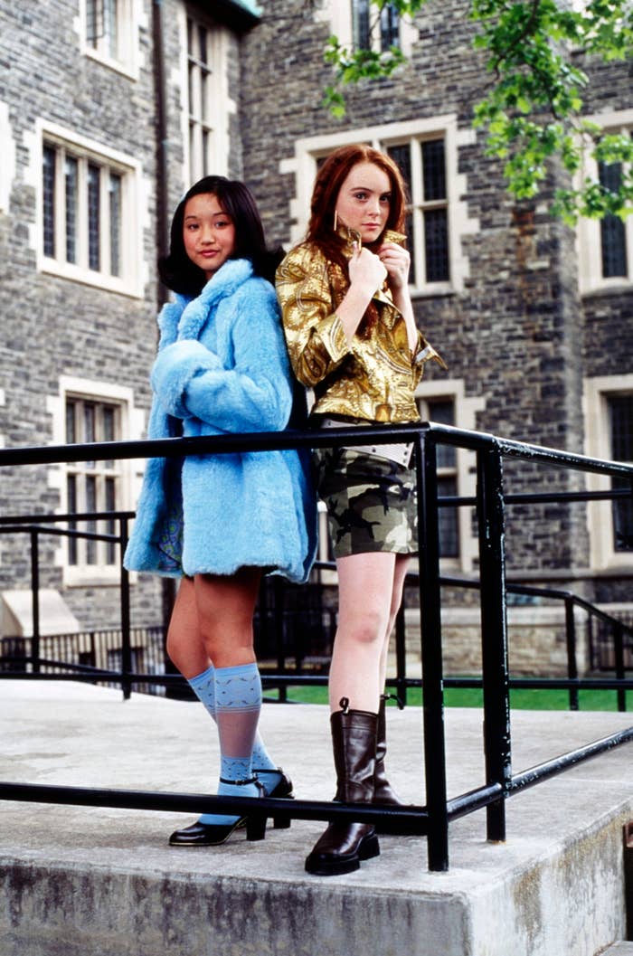 Two characters, one in a blue fur coat and the other in a gold jacket, stand on a balcony from the film Clueless