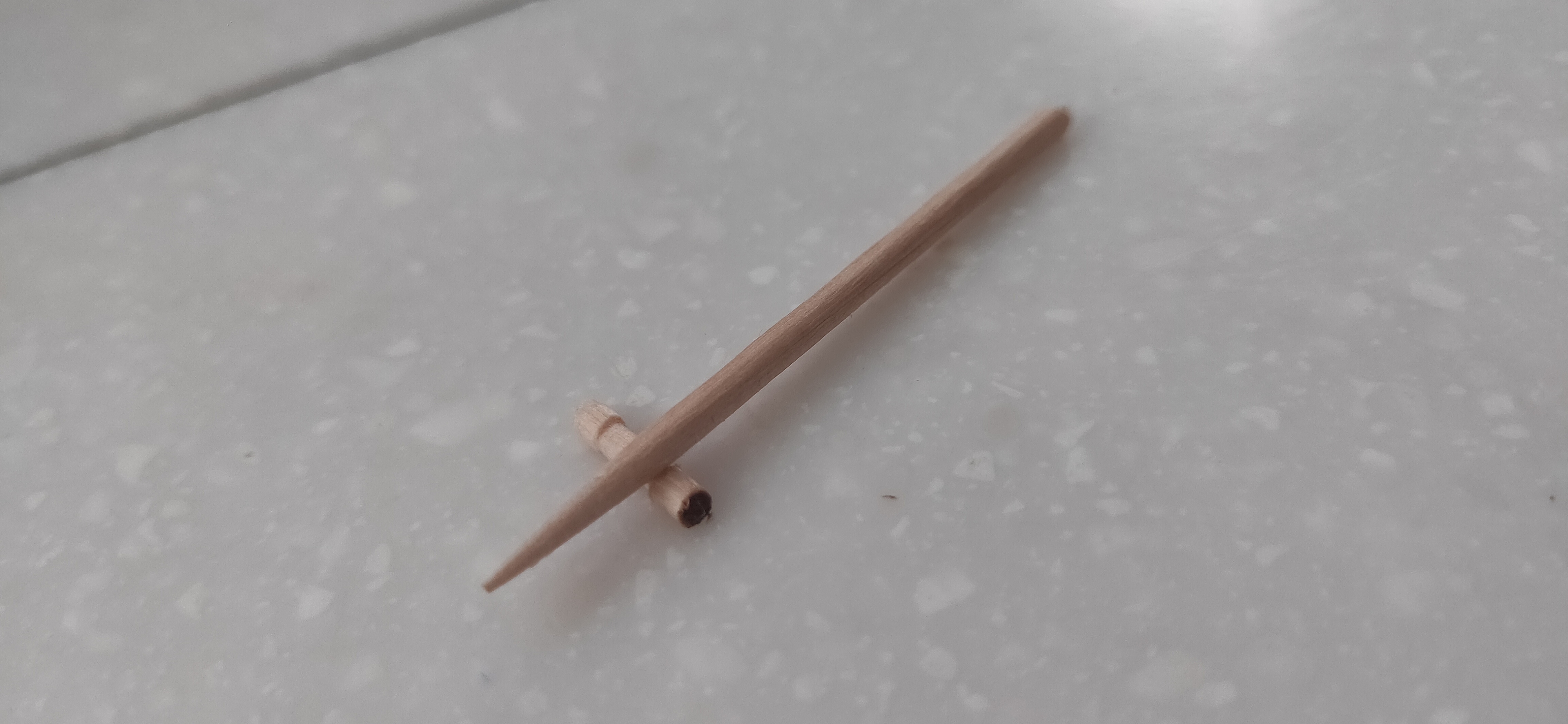 A single pencil with a broken tip lying on a flat surface