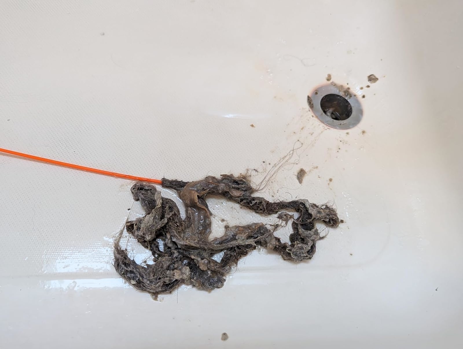 Drain clog removal tool extracting buildup from a sink, indicating maintenance or cleaning products