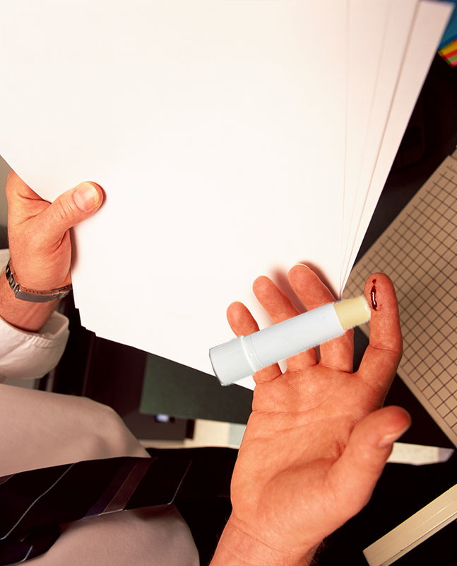 Person holding a marker and flipping through a stack of white papers on a desk