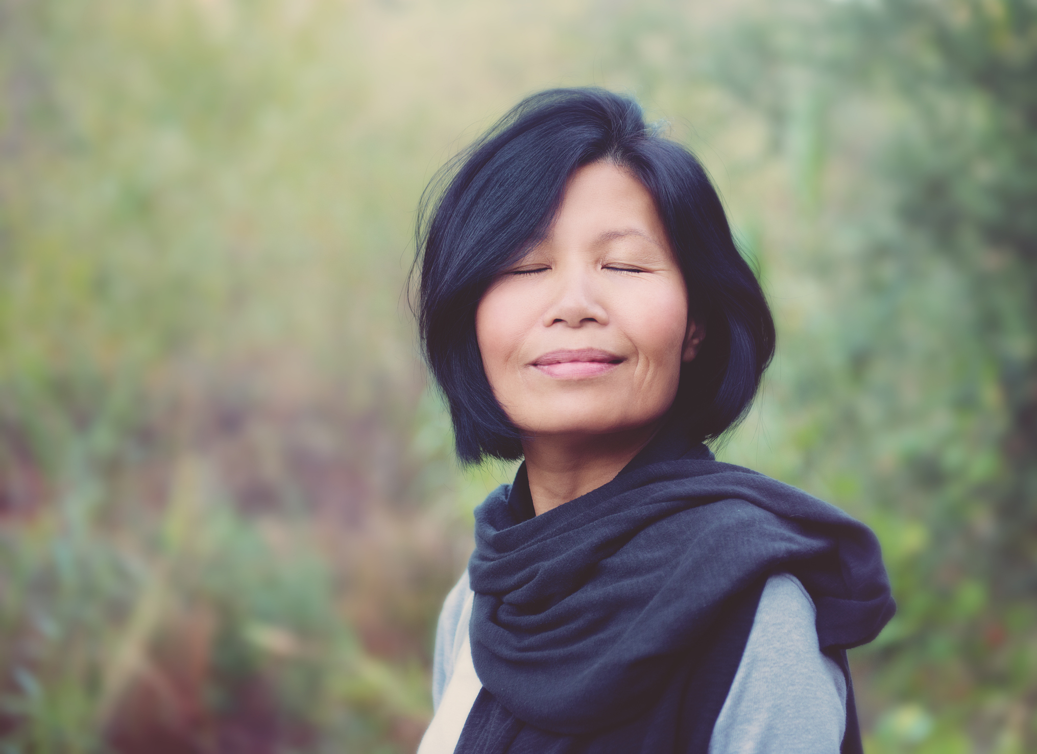 Woman with a serene expression wearing a scarf outdoors