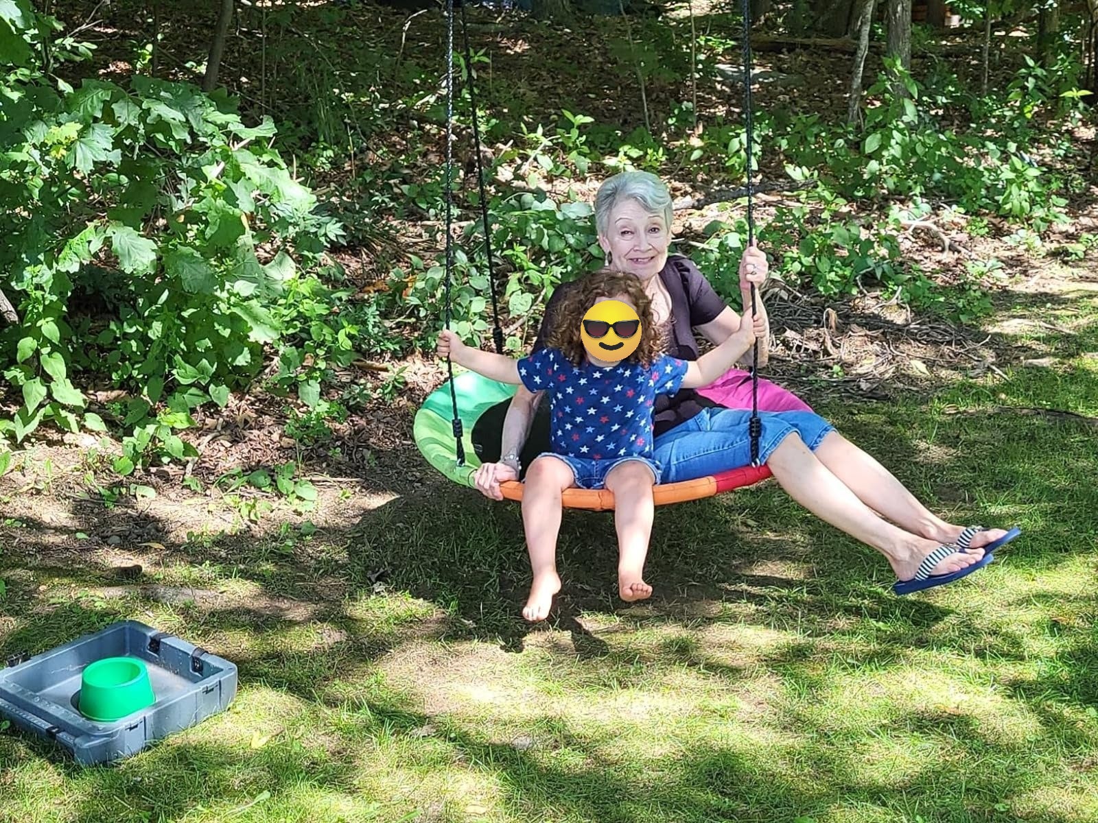 A grandparent and grandchild sitting connected  the swing