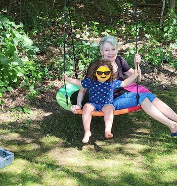 A grandparent and grandchild sitting on the swing