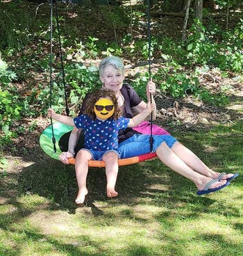 A grandparent and grandchild sitting on the swing