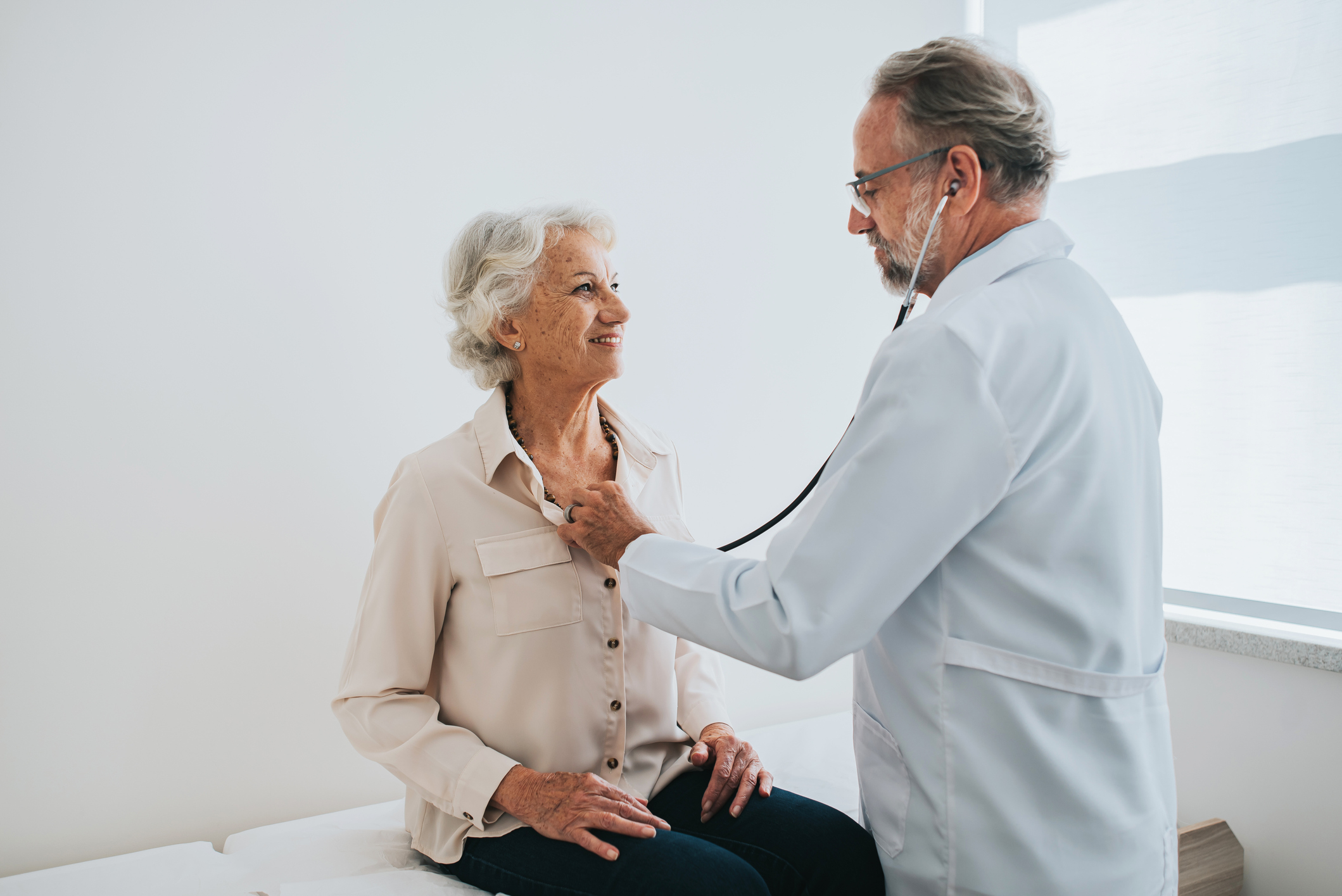 Doctor with a stethoscope examining a smiling elderly woman