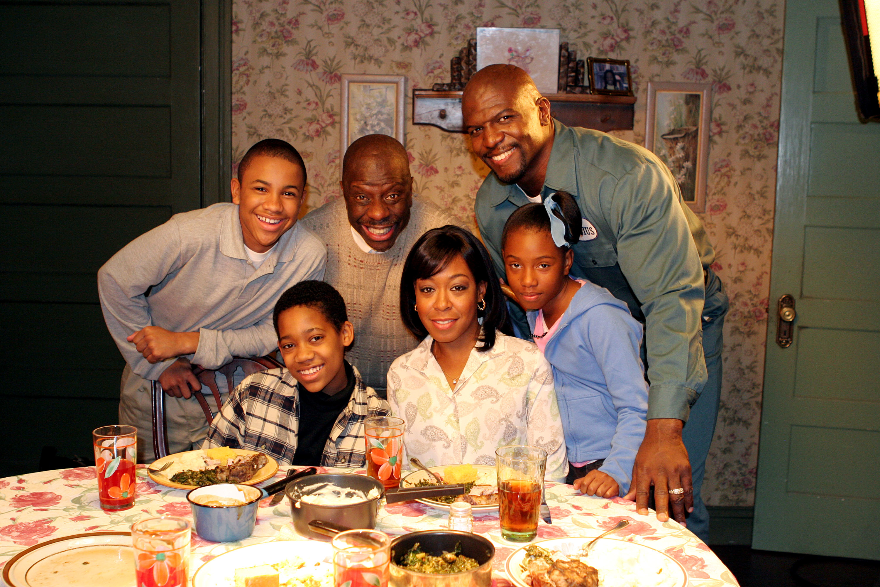 Family photo with five people smiling at a dining table, appearing in a home setting