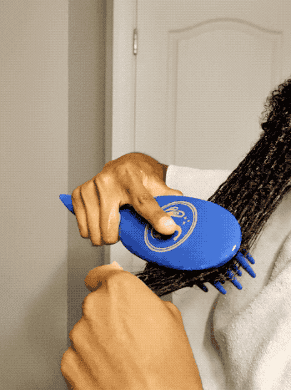 Person using a blue, circular hairbrush on their long hair