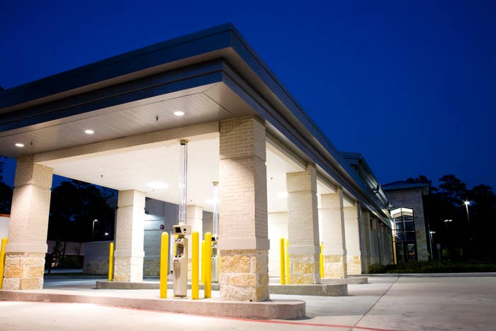 Drive-thru banking area with multiple ATM machines under a well-lit canopy at dusk