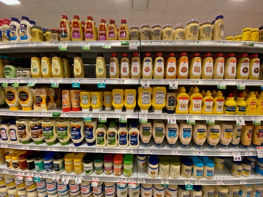 Supermarket shelf stocked with various brands and types of condiments