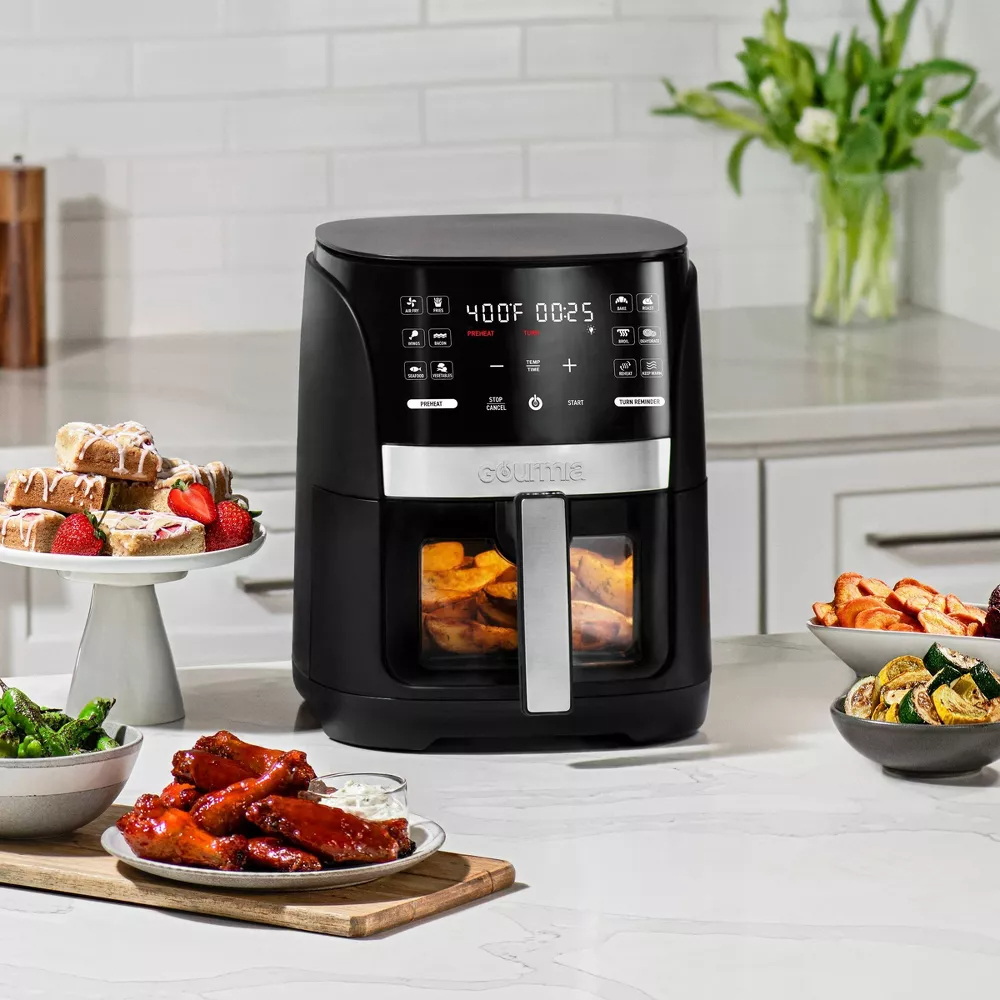 Air fryer on kitchen counter with various cooked foods around it