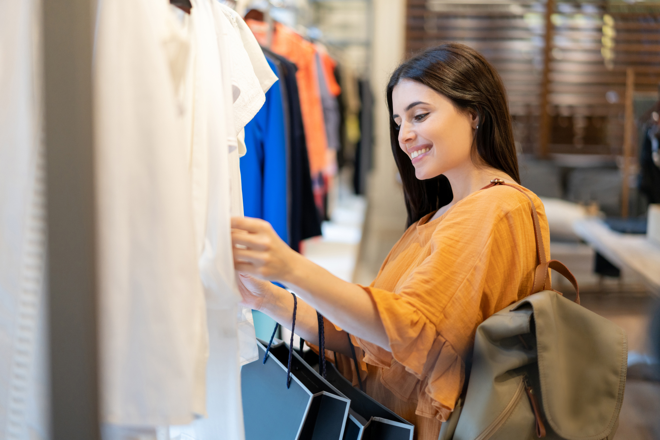 Woman browsing clothing at a store with a backpack, possibly shopping for work attire