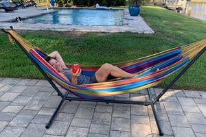 a reviewer laying in a hammock with drink in hand