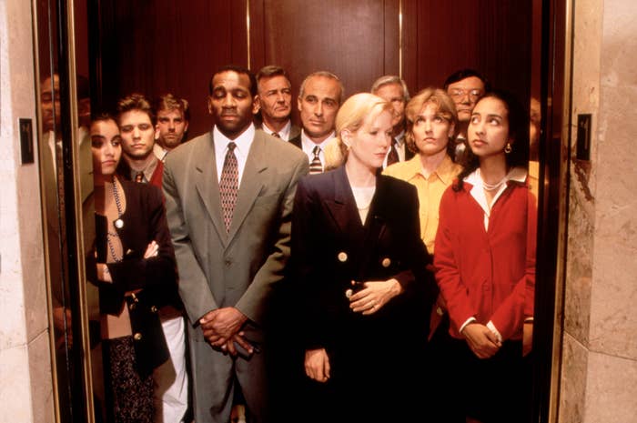 Group of people in business attire standing tightly in an elevator, looking forward