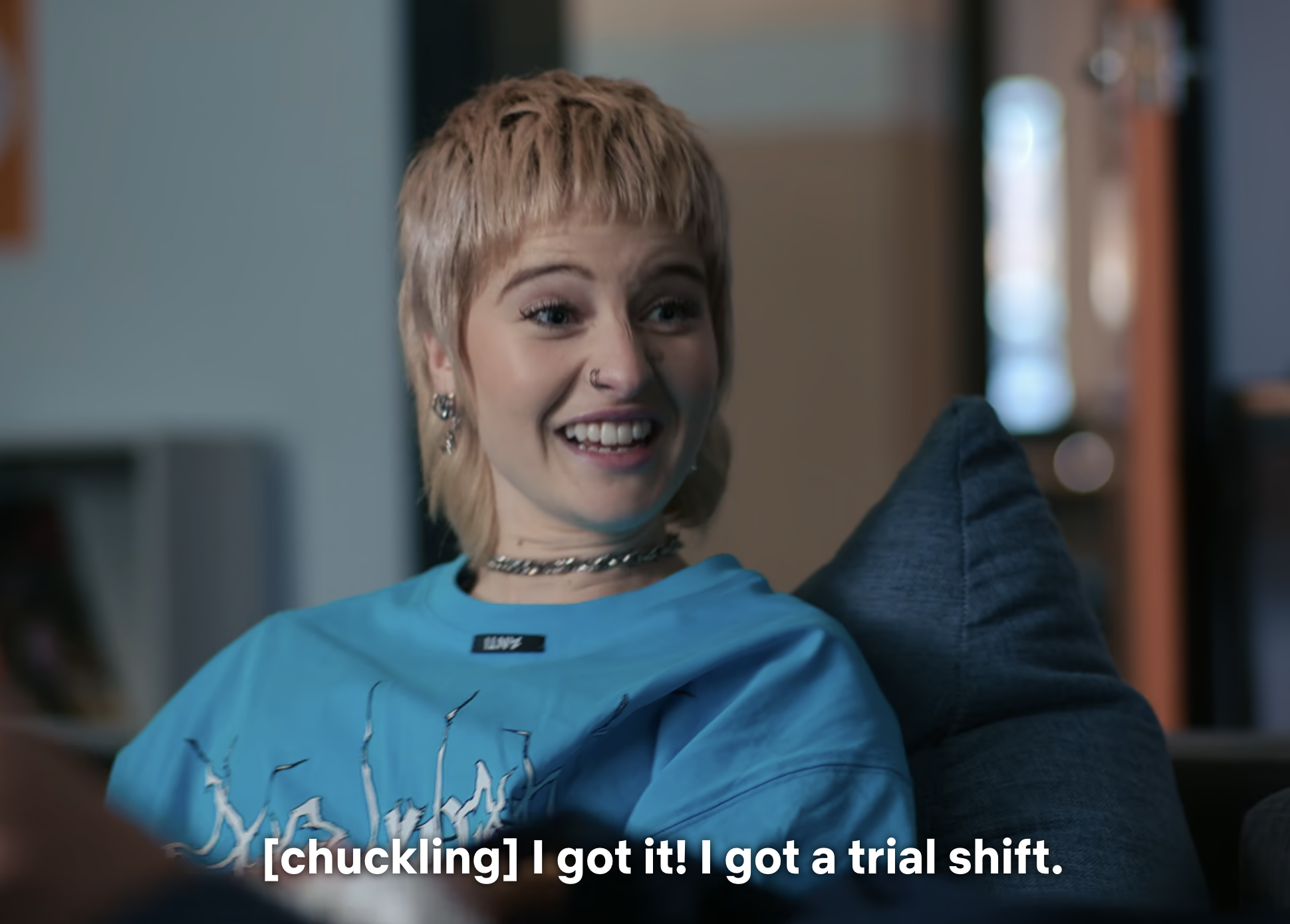 A woman smiling on a sofa with subtitles, expressing joy about getting a trial shift