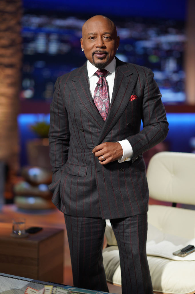 Daymond John in pinstripe suit with tie and pocket square on a TV show set