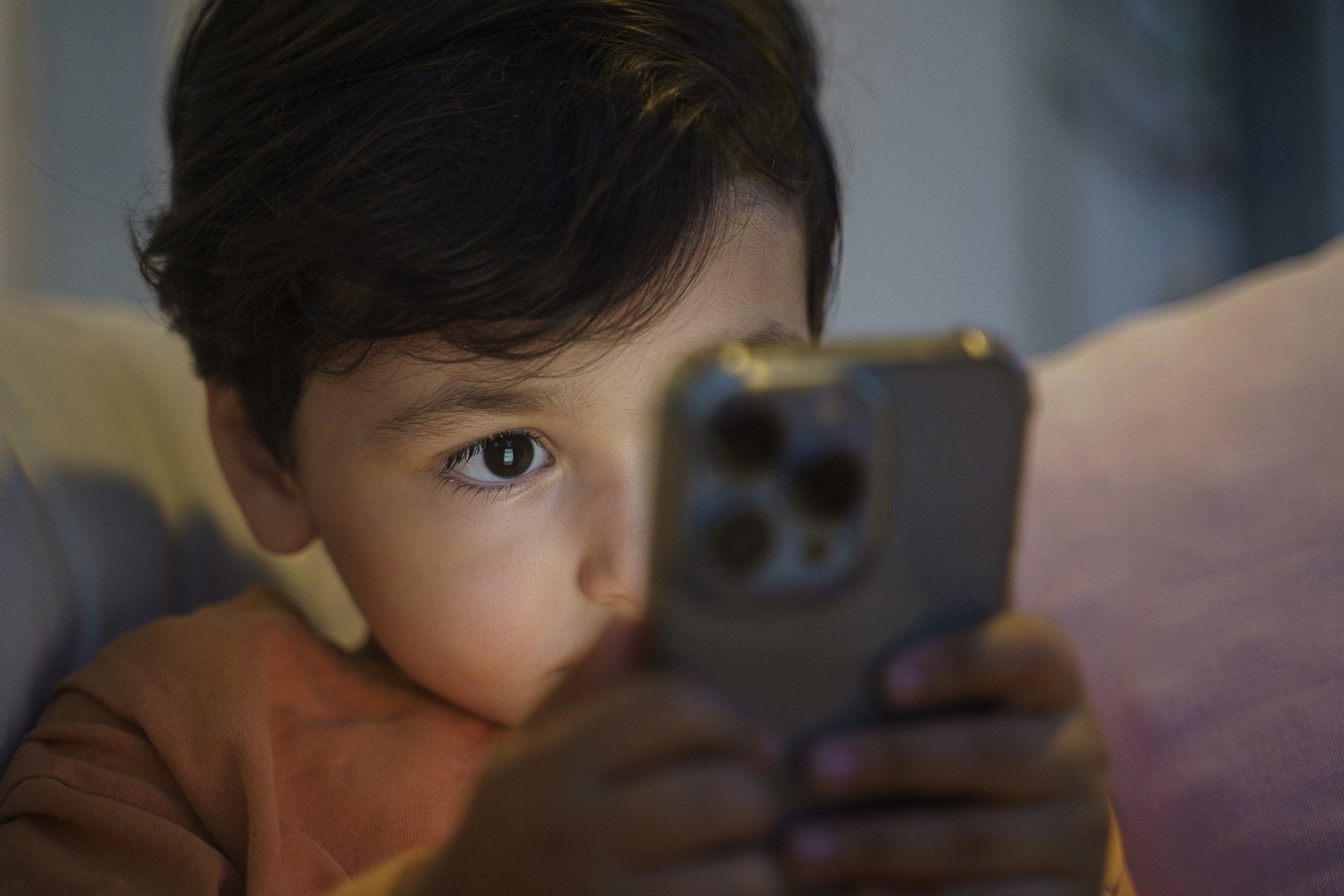 Child focused on using a smartphone, half-face visible