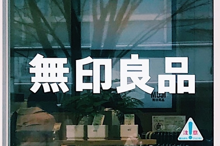 窓ガラスに「無印良品」と書かれた店舗の看板。