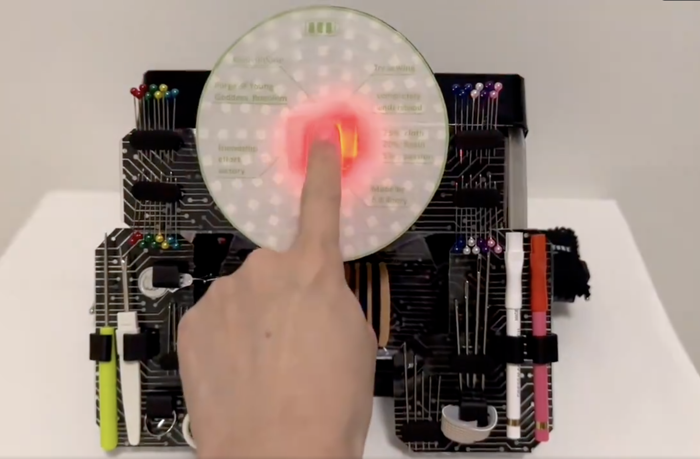 指が半透明なディスクを触り、回路基板に囲まれています。