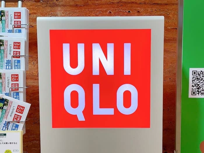Sign with &quot;UNIQLO&quot; logo displayed prominently, flanked by QR codes and pamphlets