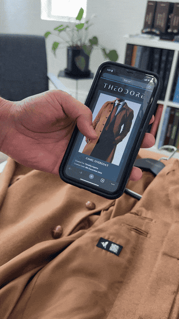 Person holding smartphone displaying an ad for a camel overcoat
