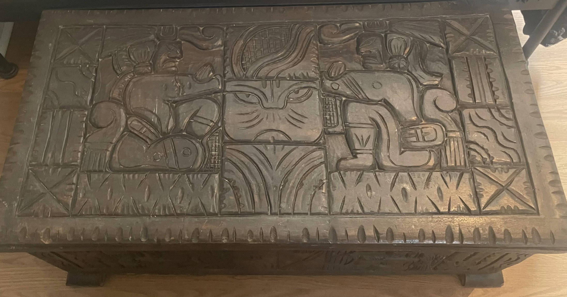 Carved wooden chest with intricate designs and animals, displayed indoors as a unique furniture piece
