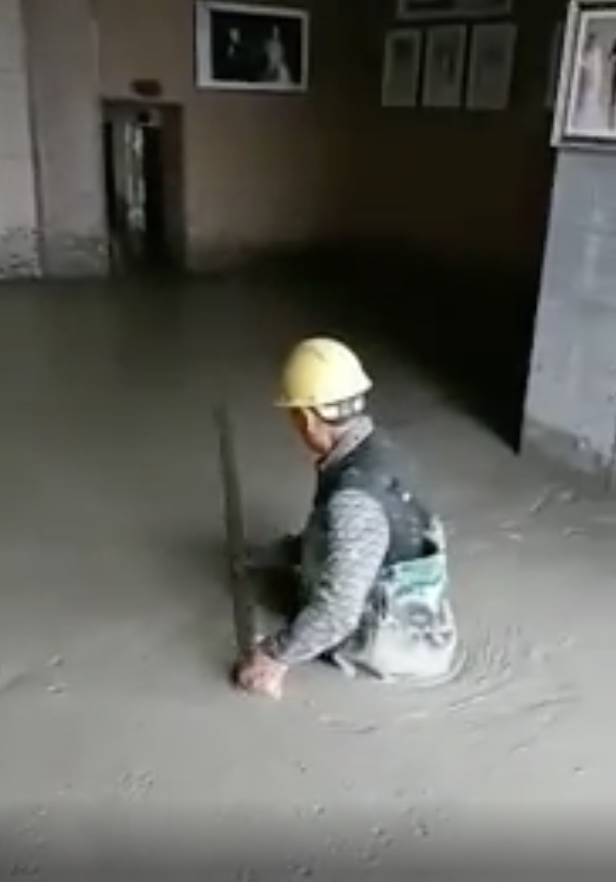 A man working waist-deep in concrete