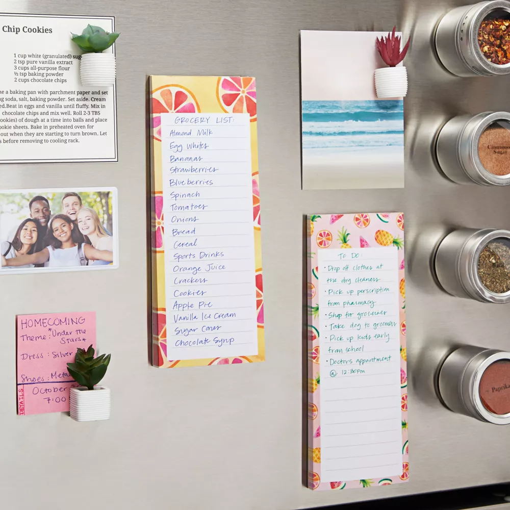 Magnetic fridge notepad with grocery list, sticky notes with various lists, and a photo, all on a refrigerator door