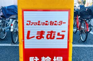 Japanese sign with text, bikes in background. Summarized: "Folding car and bike parking lot here."