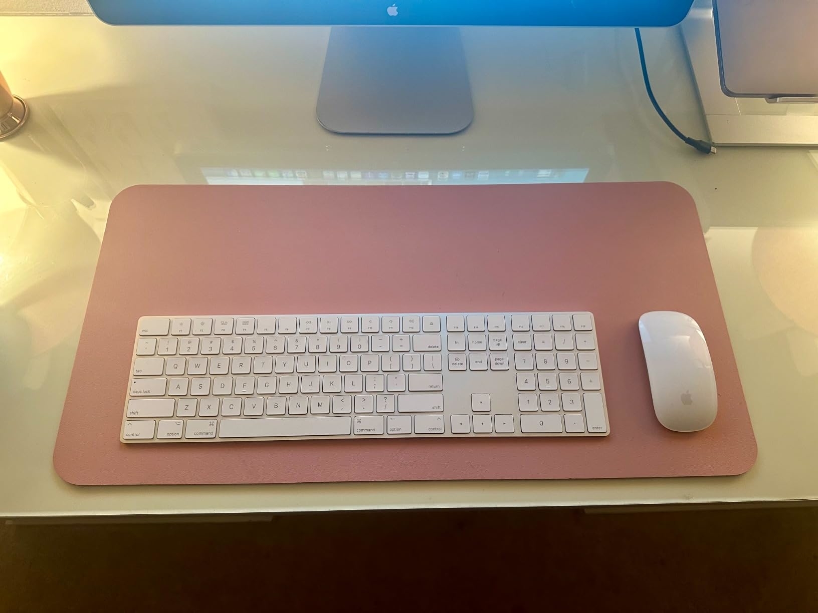 Computer desk with a white keyboard and mouse on a pink mat, technology setup for online shopping