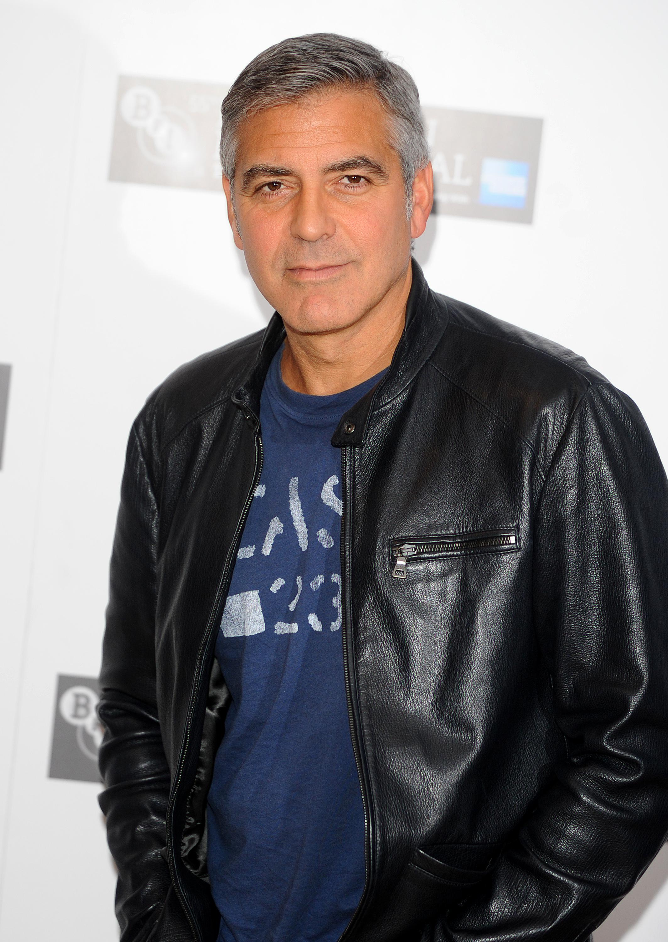 Man in a leather jacket over a graphic tee posing at an event