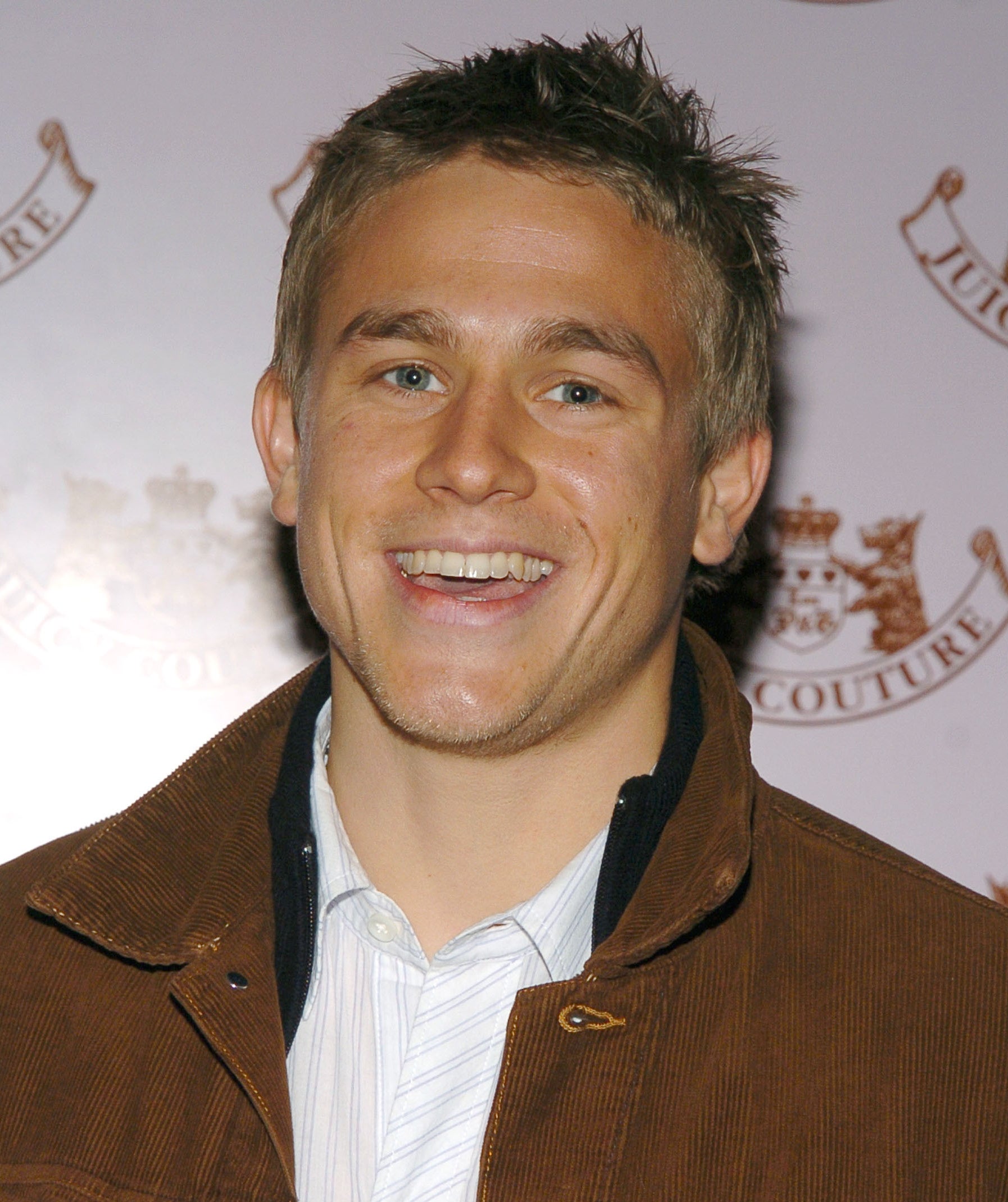 A younger Charlie Hunnam smiling widely at an event