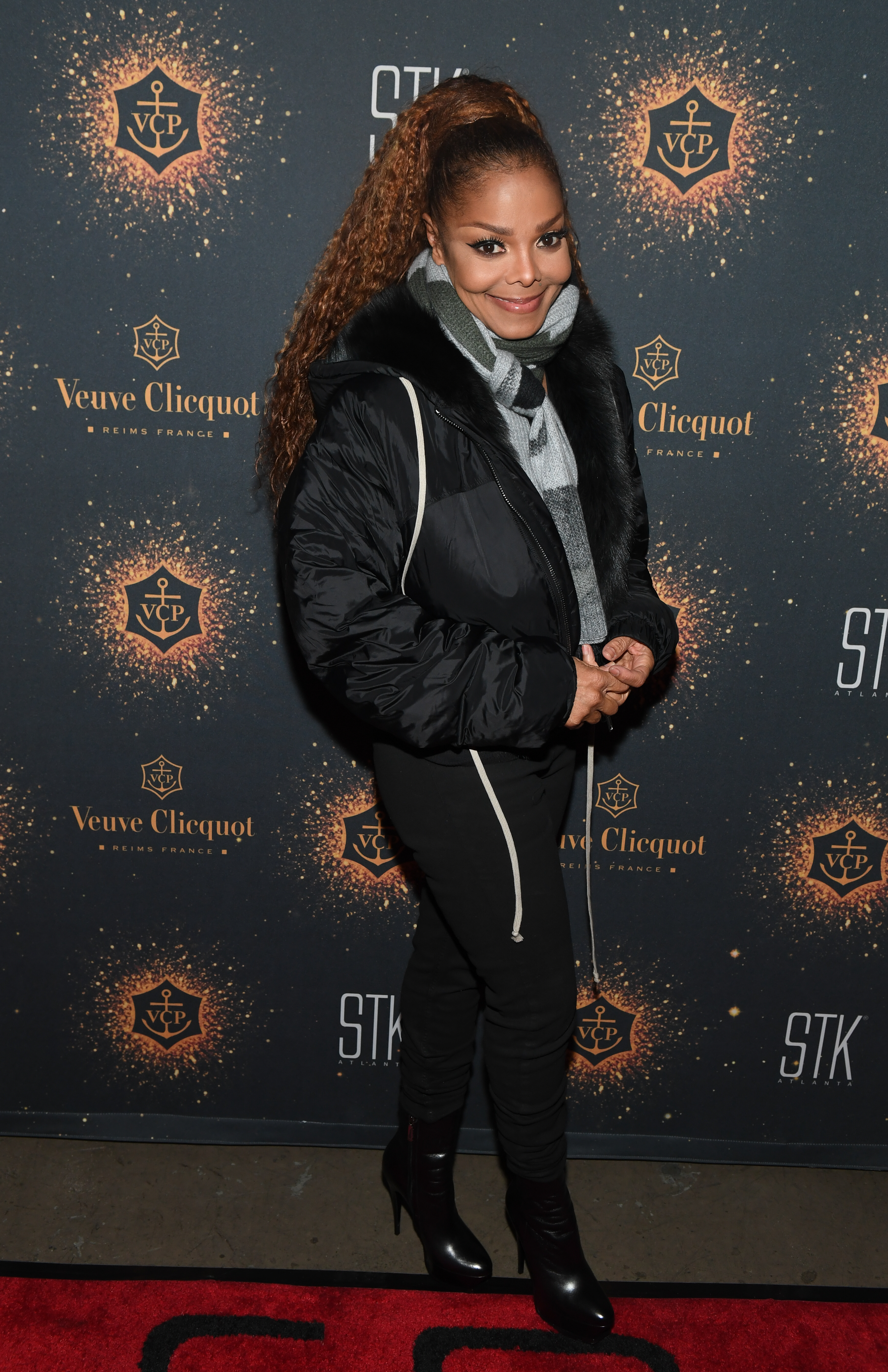 Janet Jackson in a puffy jacket and boots posing at an event
