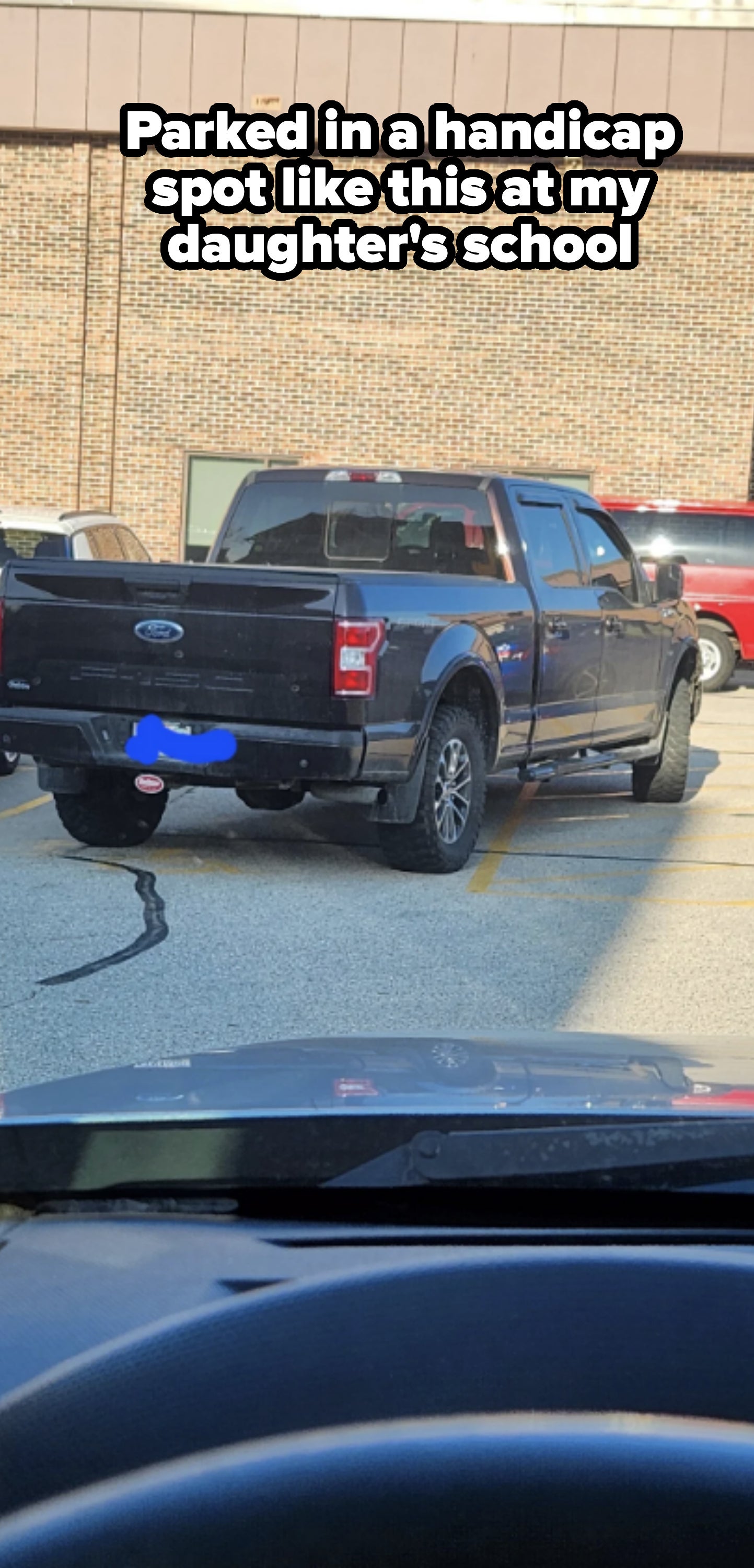 Blue pickup truck parked diagonally across two parking spots